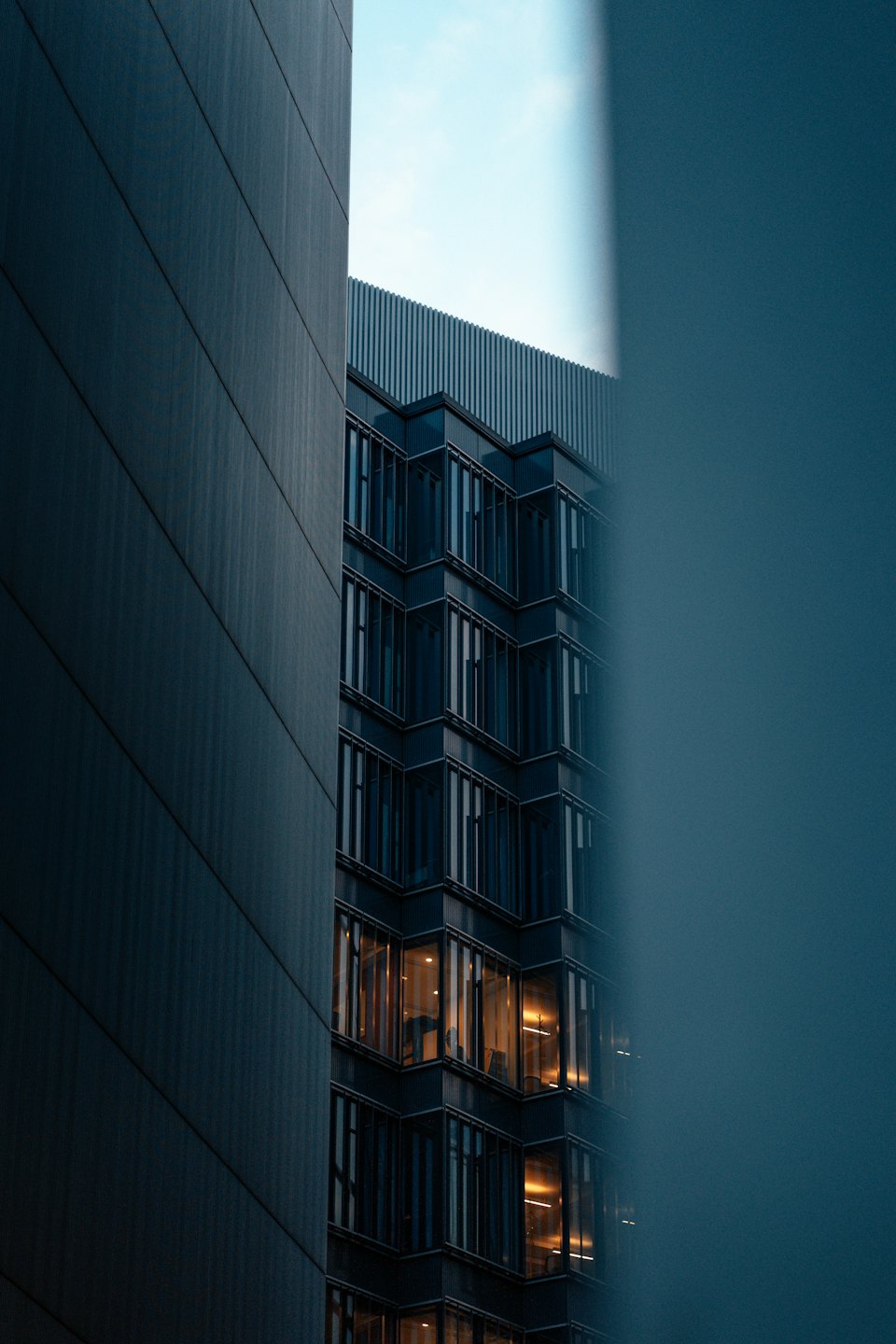 Modern office building with warm interior lights at dusk.
